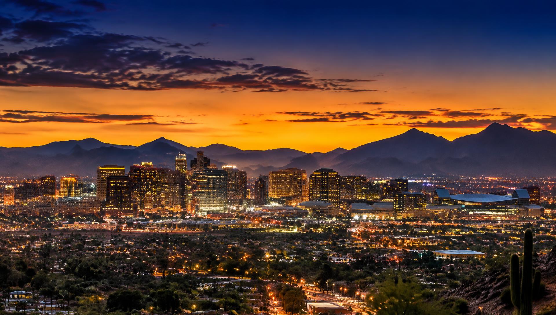 Desert city skyline at dusk with mountains behind